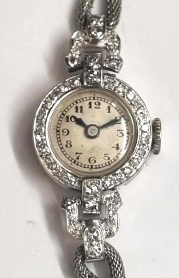 Ladies Swiss platinum and diamond hand wound cocktail watch c1930s on a rope effect white metal bracelet with adjustable catch. Silvered dial with black Arabic hours and minute track and black hands. Swiss A.Schild 15 jewel jewelled lever movement with split bi-metallic balance and case back marked 'All Platinum' and numbered 876.