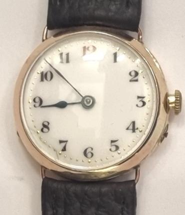 Swiss WWI Officers Style manual wind wrist watch in a 9ct gold case by the Stauffer & Son Company on a brown leather strap with gilt buckle. White enamel dial with red '12' and other black numeric hours with blued steel hands. Swiss signed jewelled lever movement with pin set rocking bar mechanism with case back bearing a London import hallmark for c1914 and numbered 267171.