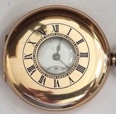 English made half hunter pocket watch in a 9ct gold Dennison case with top wind and time change and hallmarked for Birmingham c1910. Black Roman hours on the outer case and internal white enamel dial with black Roman hours and gilt hands with a subsidiary seconds dial at 6 o/c. English 3/4 plate jewelled lever movement with split bi-metallic balance and overcoil hairspring and numbered 814710 with case back numbered 26960.