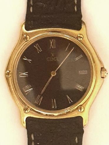 Gents Swiss made Ebel quartz wrist watch in an 18K gold case with leather strap and 18K gold deployment buckle. Black dial with polished gilt hands and matching Roman hour markers.