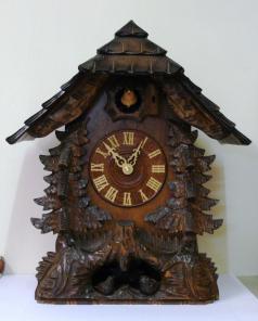 New quartz mantel / wall cuckoo clock by Harzer. Pine wood case with stylised pine tree decoration and nesting bird motif. Traditional carved light coloured wood chapter ring with roman hours and matching wooden hands. Visible pendulum and carved light wood cuckoo bird display on the hour.  Dimensions: Height - 16.5", width - 13.5", depth - 10".