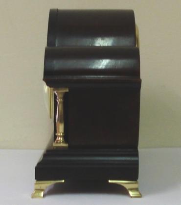 French 8 day mantel clock timepiece in an impressive triple arched dark mahogany case with gilt brass columns and bracket feet. Gilt brass bezel with convex glass over a white enamel dial with black Arabic hours and black steel hands. Brass drum case movement maker unknown stamped 'France' with a good quality replacement lever escapement platform and a captive winding key.    Dimensions: Height - 11", width - 6", depth - 3.5".