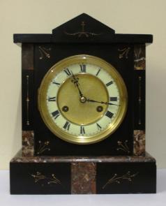 German 8 day slate and marble cased mantel clock circa 1900 by Jungans. Architectural square case with decorative engraved decoration with gilt infill. Gilt circular bezel with flat chamfered glass and white enamel chapter ring with a matt gilt interior together with black roman hours and ornate blued steel hands. Good quality spring driven, gong striking movement, regulated by a pendulum and with the Junguns touch mark.  Dimensions: Height - 11.5", width - 9.5", depth - 5.5".