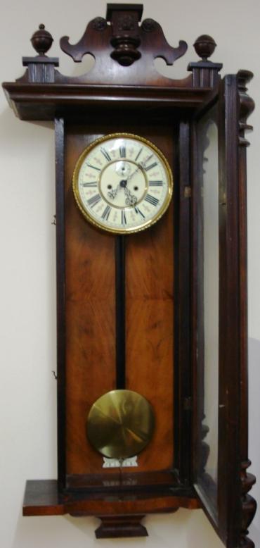 Clock for sale for restoration:- Vienna Regulator style mahogany and walnut cased gong striking wall clock by the Regulatorfabrik Germania Co. Crested pediment full length door with turned side columns, original glass over white enamel dial with black roman hours, ornate blued steel hands and subsidiary seconds dial. Good quality brass 'A' frame weight driven pendulum regulated 8 day movement circa 1880. Back plate displays the Regulatorfabrik Germania mark and is numbered #228746. Lacks some finials, weights and one weight pulley.