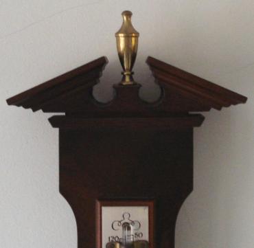 Modern Comitti of London compensated barometer in a walnut veneer case with brass finial. Circular gilt brass bezel over a silvered dial with black painted dual pressure index and a separate alcohol Centigrade and Fahrenheit thermometer.