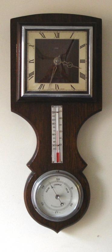 British made oak cased 8 day clock and aneroid barometer. Square chromed bezel with domed glass over an ivory chapter ring with black painted roman hours and chromed hands. Circular chromed bezel over a silvered dial barometer with inches of mercury index. Separate alcohol Fahrenheit and Centigrade thermometer. Clock movement hinges forward to reveal time change, fast / slow adjust and wind controls.