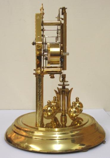 German 400 day Anniversary time piece maker unknown. Glass dome over triple stepped, level adjustment base with two engraved movement support columns. Diamond shaped gilt bezel over silvered engine turned dial plate with black arabic hours and matching black  hands. Standard brass 'anniversary' going movement with suspended oscillating slow / fast adjustable pendulum and base located locking mechanism for transportation.