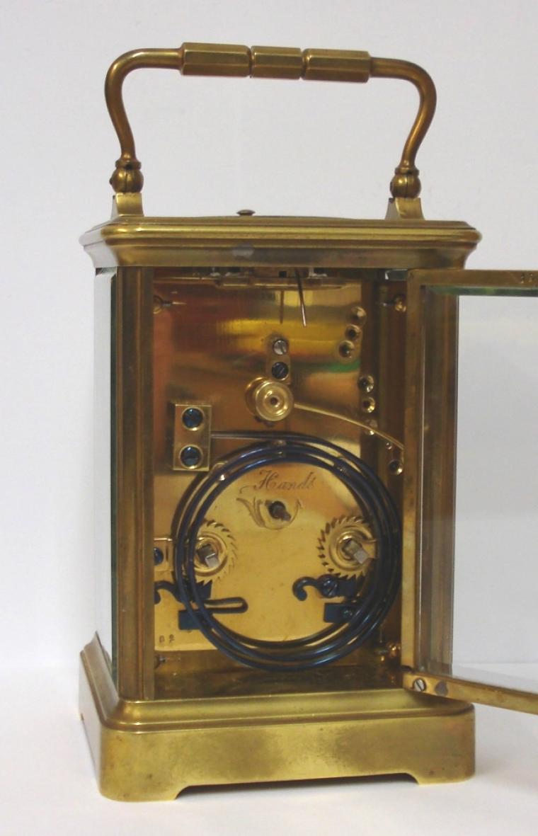French gilt brass and 5 glass, 8 day strike / repeat carriage clock circa 1880 by Henri Jacot. Corniche case with chamfered glass panels throughout, white enamel dial with black Roman hours and minute track and blued steel hands. Back plate with Jacot arrow and numbered #6702 below a contemporary silvered jewelled lever escapement. 'Hidden' oval Henri Jacot stamp applied internally to the back of the dial plate. Height - 7.25" Width - 3.75" Depth - 3.25"..