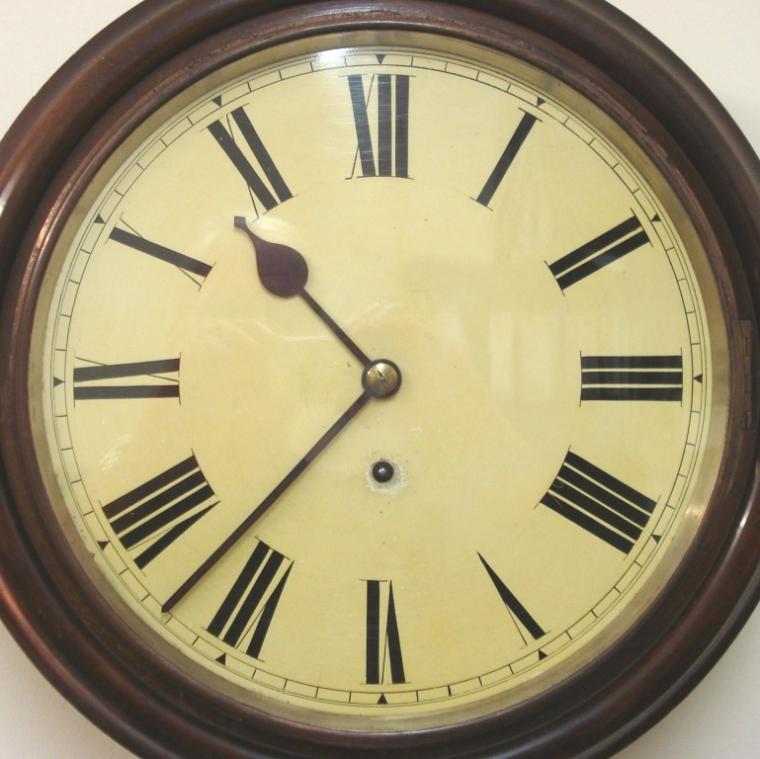 Black Forest 8 day wall clock by Winterhalder, Hofmeier and Schwaerzenbach in a circular dark wood case. Brass bezel with flat glass over an ivory painted dial with black roman numerals and black painted steel hands with single winding square. Spring driven, pendulum regulated, brass time piece movement circa 1900.  Dimensions: Height - 17", Width - 17", Depth 5".