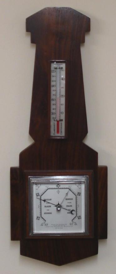 British dark walnut solid wood aneroid barometer circa 1920. Square chromed bezel with flat chamfered glass over a silvered dial with black painted pressure index, blued steel pressure indicator and silvered history pointer. Separate red alcohol Fahrenheit and Centigrade thermometer.  Dimensions: - Height 20", width 7.5", depth 2.5".