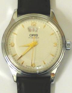 Oris 7429 All Stainless Steel manual wind wrist watch on a black leather strap with silver buckle. Silver textured dial with polished gilt hour markers and matching hands with sweep seconds and date display at 12 o/c. Swiss made Oris 17 jewel incabloc movement with screw-on case back water resistant to 30m.