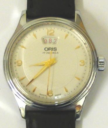 Oris 7429 All Stainless Steel manual wind wrist watch on a black leather strap with silver buckle. Silver textured dial with polished gilt hour markers and matching hands with sweep seconds and date display at 12 o/c. Swiss made Oris 17 jewel incabloc movement with screw-on case back water resistant to 30m.