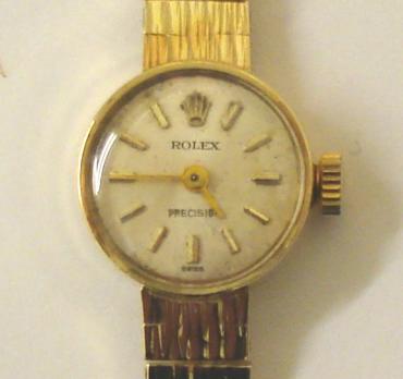 Ladies Rolex Precision 9ct gold manual wind wrist watch with integral gold bark effect bracelet. Silvered dial with gilt baton hour markers and matching hands. Signed Rolex 18 jewel calibre 1400 movement with Rolex case numbered #33379 with London hallmark for 1967.