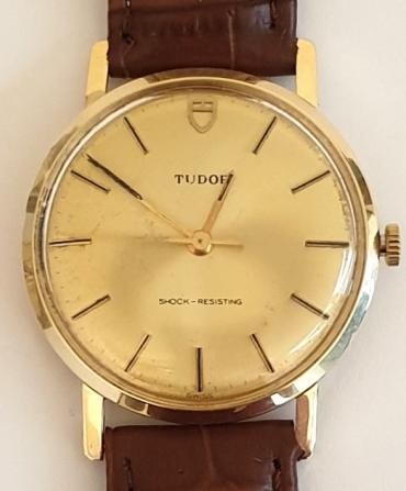 Rolex Tudor manual wind wrist watch in a 9ct gold case with brown leather strap and gilt buckle. Champagne dial with black insert baton hours and matching polished gilt hands and sweep seconds hand. Signed Tudor calibre ETA 2750 17 jewel movement in a signed 9ct gold case with a London import hallmark for 1975, model 9801 and numbered 609245.