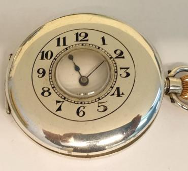 Swiss half hunter pocket watch in a silver case with a London import hallmark for 1918 with top wind and time change. External black Arabic chapter ring on the outer case, internal white enamel dial with black Arabic hours and blued steel hands with a subsidiary seconds dial at 6 o/c. Swiss 17 jewel unsigned jewelled lever movement with overcoil hairspring and split bi-metallic balance.