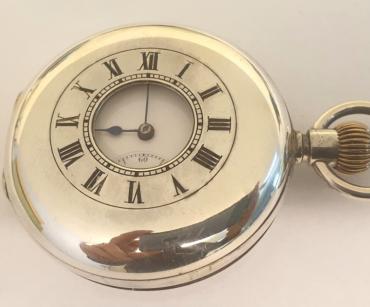 Swiss IWC Peerless half hunter pocket watch c1900 in a silver case with top wind and time change. External black Roman chapter ring on the outer case, internal white enamel dial with black Roman hours and blued steel hands with a subsidiary seconds dial at 6 o/c. Swiss signed and numbered jewelled lever movement with split bi-metallic balance and overcoil hairspring, the silver case inscribed 'Exam,,d by Goldsmiths Company, 112 Regent Street, London' and numbered 303857.
