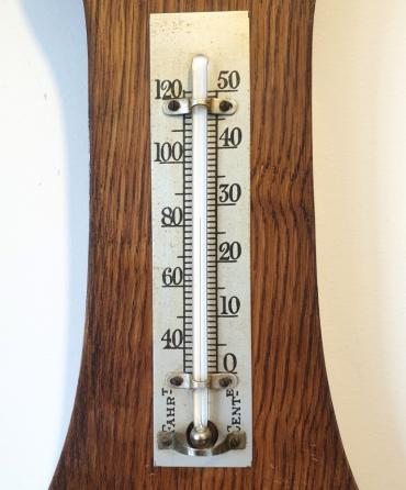 English carved dark oak mounted aneroid barometer and thermometer, circa 1930s. Circular silvered brass bezel with chamfered flat glass over a white dial with black inches of mercury pressure index and a blued steel pressure indicating hand with a gilt history marker hand together with a mercury thermometer displaying temperature in both Fahrenheit and Centigrade.