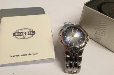 Modern Boxed and Unused quartz wrist watch by Fossil. Stainless steel case with integral bracelet and a stainless steel back. Deep blue reflective sunburst dial with polished silvered and luminous hour markers and matching angular hands together with a central seconds hand and date display at 3 o/c. Case water resistant to 100 metres / 330 feet and complete with original box and papers.