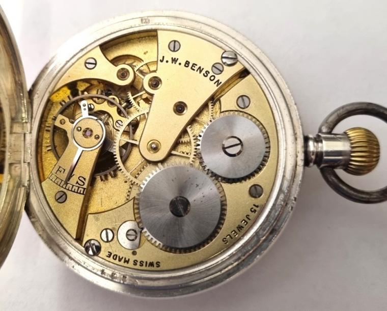Swiss half hunter pocket watch by J.W. Benson in a silver case with top wind and time change. External black Roman hours on the outer case and internal signed white enamel dial with black Arabic hours and gilt hands and subsidiary seconds dial at 6 o/c. Swiss signed 'J.W. Benson' 15 jewel jewelled lever movement with bi-metallic balance. The 'J W B' silver case bearing a London hallmark for c1936 and numbered 656224.