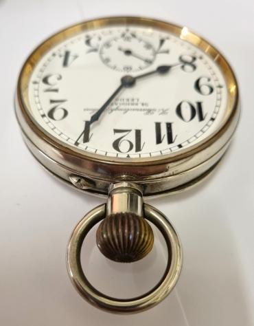 Heavy nickel cased Goliath pocket watch retailed by Barraclough & Sons of Leeds in an original plush velvet lined watch stand box. Top wind and pin set rocking bar time change with a white enamel dial and black Arabic hours with blued steel hands and a subsidiary seconds dial at 6 o/c. Swiss jewelled lever movement by Doxa with glass dust cover protection.