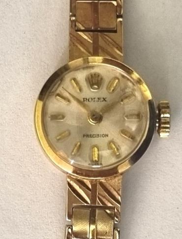 Ladies Rolex Precision dress watch in a 9ct gold case hallmarked for London c1965 with an integral 9ct gold bracelet. Signed Rolex Precision champagne coloured dial with polished gilt baton hours and matching hands. Swiss signed Rolex Geneve 18 jewel jewelled lever movement calibre 1401 with case back numbered 25910.
