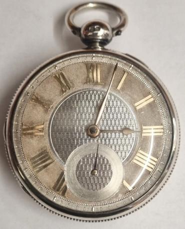 English unsigned silver cased verge fusee pocket watch hallmarked for London c1823. Key wind and time change with silver dial and gilt Roman hours and matching hands with blued subsidiary seconds hand. Silver coin edge case and engraved back plate with decorated cock piece and diamond end stone verge fusee movement numbered 1607.