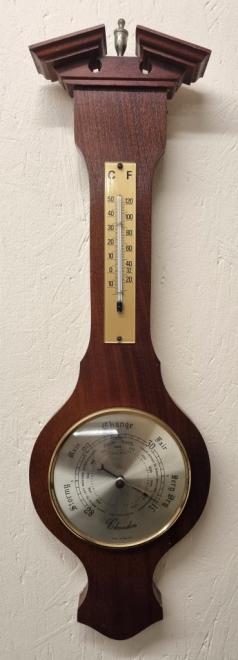 Modern English mahogany cased aneroid barometer and thermometer. Circular gilt bezel with convex glass over a silvered dial with black inches of mercury pressure index and a blued steel pressure indicating hand with a gilt manual marker hand together with an alcohol thermometer displaying temperature in both Centigrade and Fahrenheit. Height - 19" and width - 6".